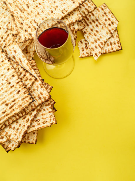 传统的犹太面包——无酵饼和一杯黄色背景的红酒。低角度的观点。照片里没有人。有一个空位可以插入。犹太人的逾越节。图片下载
