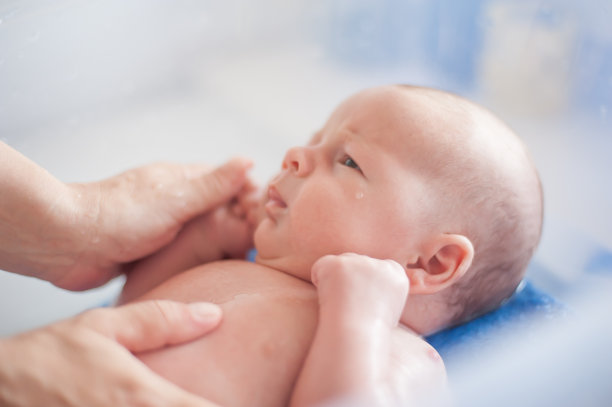 婴儿洗澡。妈妈正在给可爱祥和的新生婴儿洗澡图片下载