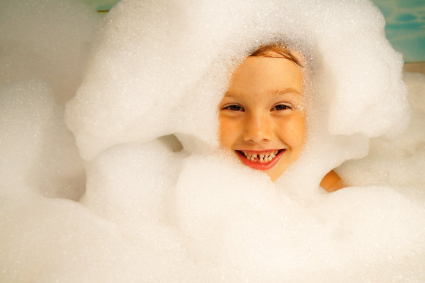 小女孩用沐浴泡沫洗澡。他脸上挂着微笑。儿童卫生、健康、清洁。图片下载