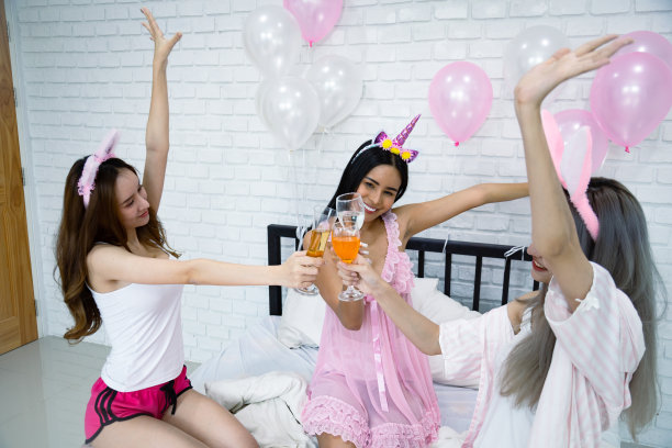 一群性感女孩在卧室喝酒。图片下载