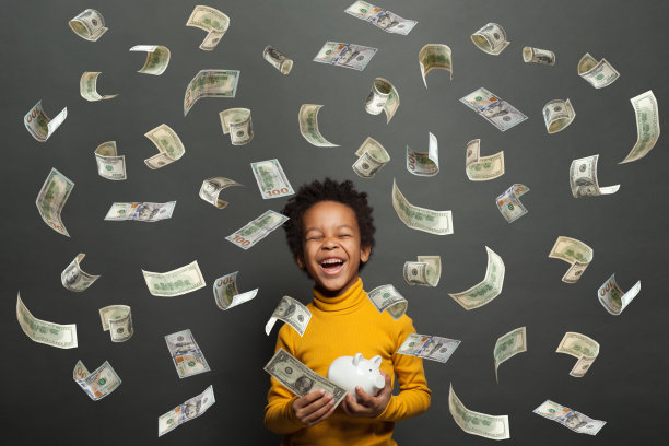 快乐的非洲裔美国孩子笑着，拿着白色的储蓄罐在黑色的背景上美元的钱雨图片下载