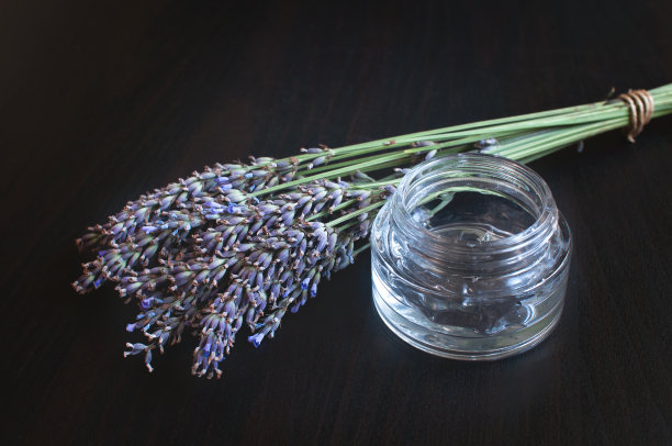 玻璃罐，透明凝胶和新鲜的薰衣草花在深色图片下载