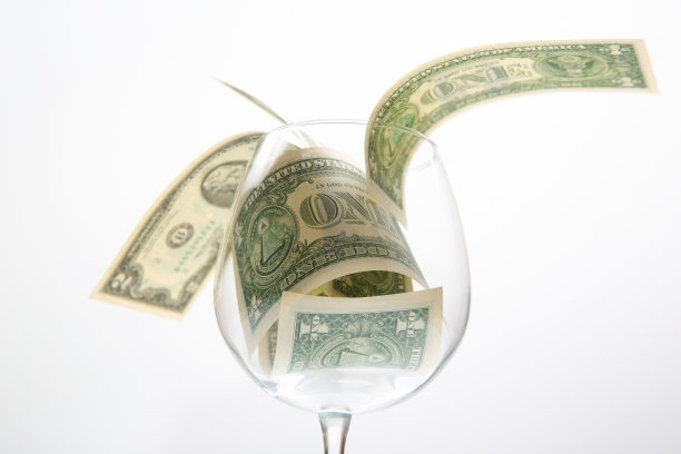 一美元纸币的钱躺在一个空的酒杯。葡萄酒行业的商业酒精营销图片下载