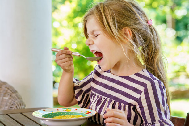 学龄前的小女孩用勺子吃蔬菜土豆汤。儿童健康食品。在家或托儿所的孩子都很快乐。图片下载