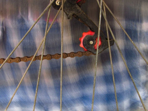 减少棘轮，链条和交叉自行车车轮辐条，与一个模糊的移动背景。图片下载