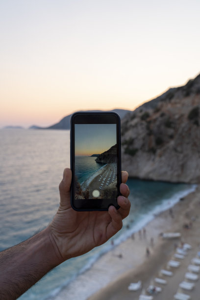 男子在海滩拍摄日落照片图片下载