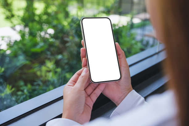 模拟形象的一个女人拿着手机与空白的桌面屏幕图片下载