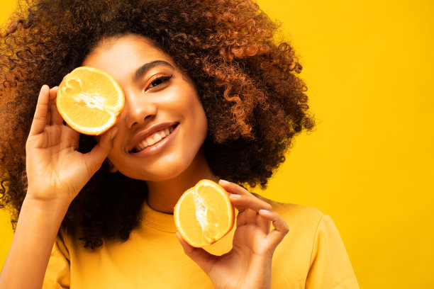 年轻深色皮肤女性隐藏眼睛的照片半片橙色穿t恤孤立在黄色的颜色背景图片下载