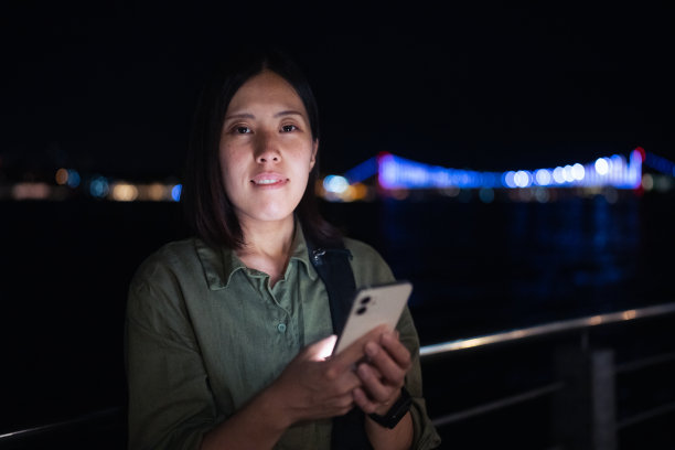 年轻女性游客晚上在城市里使用智能手机图片下载