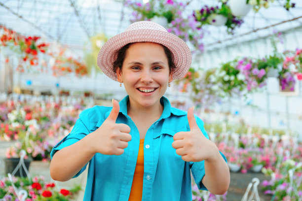 鲜花盛开的温室里，漂亮的女人笑得很开心，看着镜头，露出夸张的表情。图片下载