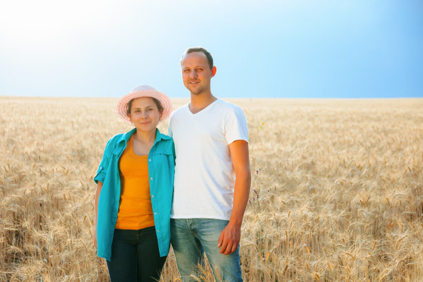 一对年轻的农学家男女站在晴空万里的麦田里，享受生活。图片下载