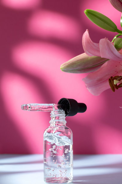 自然化妆品玻璃瓶百合和阴影在粉红色的背景。面部和身体护理水疗概念。玻尿酸油、胶原蛋白及多肽精华护肤产品图片下载