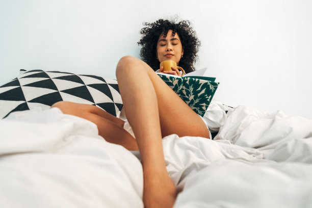 年轻的混血女性放松在家里喝茶和写日记。图片下载