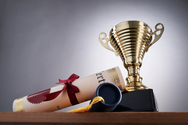 灰色背景下的金色奖杯和证书卷轴图片下载