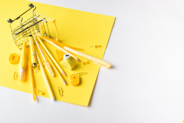 超市的购物车里放着各种黄色的文具，背景是黄色的。回到学校。横幅与办公元素的文字空间购买，销售图片下载