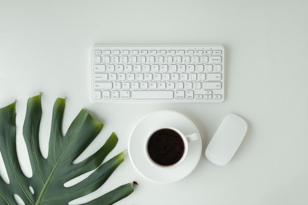 白色的GWERTY键盘，鼠标和一杯咖啡放在白色的桌面上。工作地点的概念。平的办公桌。为文本复制空间。远程办公的概念图片下载