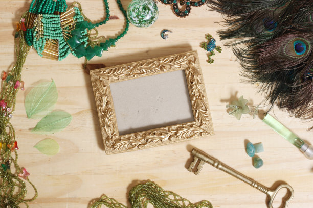 绿色珠宝和孔雀羽毛与金画框木桌图片下载