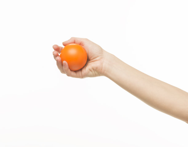 女性的手拿着一个橙色的海绵球，在白色的背景上孤立图片下载