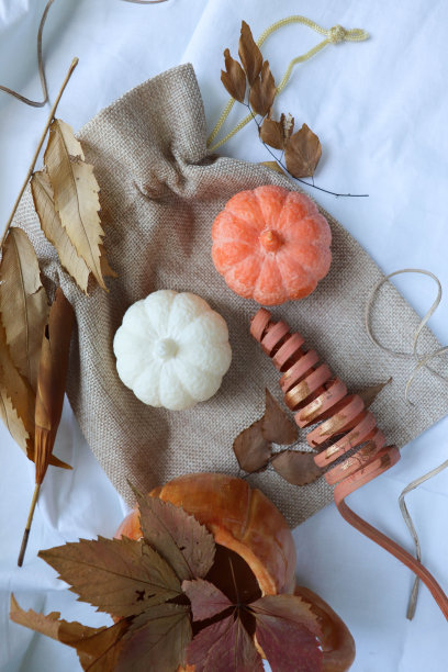 秋天的成分。陶瓷橙色杯在南瓜形状与秋天的叶子和手工大豆蜡烛在南瓜的形状图片下载