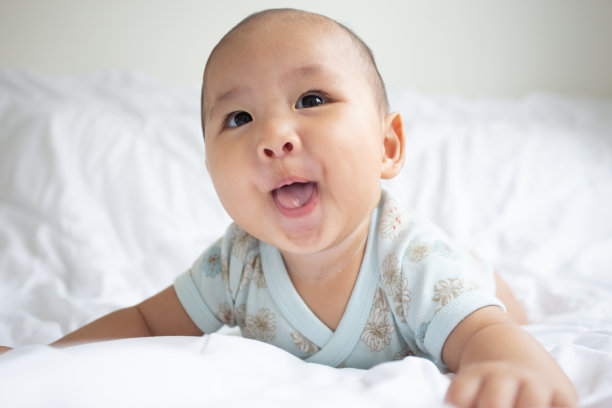 亚洲可爱宝宝在白色阳光充足的卧室。新生儿躺在床上放松图片下载