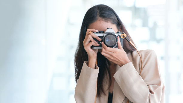 年轻的亚洲女子是一个专业摄影师与现代摄影相机。图片下载
