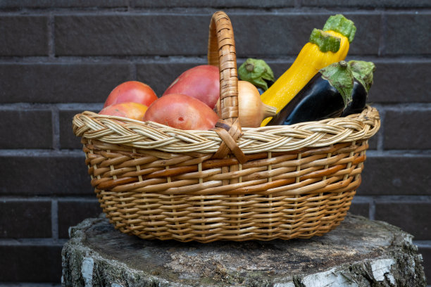 柳条木篮子装满新鲜成熟的蔬菜:西红柿，黄瓜，洋葱，西葫芦，茄子在砖的背景。早期收获。健康饮食生活方式观念饮食营养。消费者篮子图片下载
