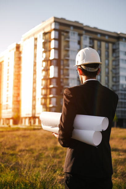 一位戴安全帽的建筑工程师检查建造的房屋，并将其与技术方案进行比较图片下载