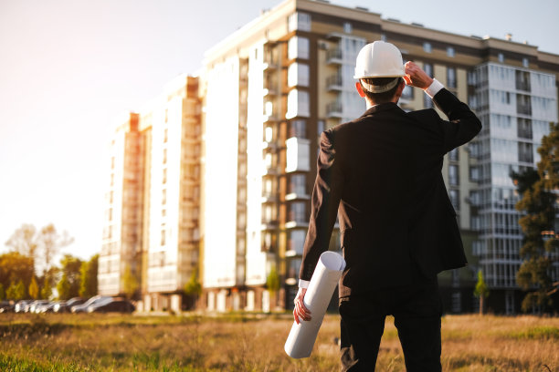 一位戴安全帽的建筑工程师检查建造的房屋，并将其与技术方案进行比较图片下载