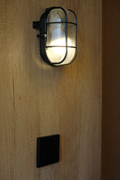开黄灯工业风格金属黑色壁灯。墙上挂着一盏褐色的木墙，夜灯。室内工业风格的装饰。极简主义。图片下载