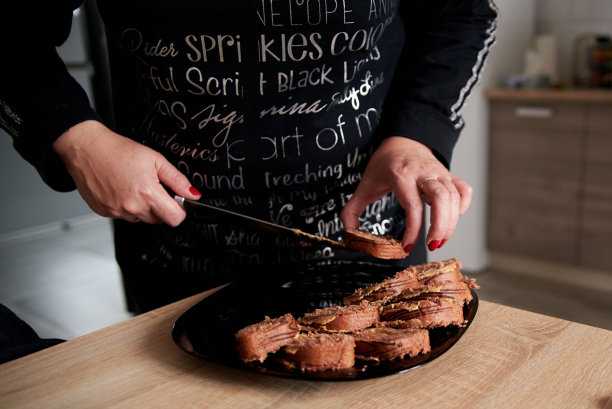 2018年10月23日，乌克兰，泰尔诺皮尔:一名女子的手的特写，正在把巧克力蛋糕放在盘子里。女人，在厨房准备茶点。家里舒适。舒适的家。甜的食品消费。图片下载