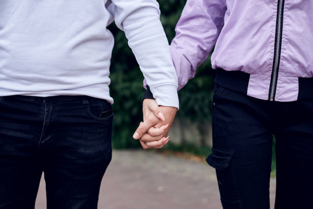 一对相爱的年轻情侣手牵手在公园里。女友和男友的特写照片，站在街上散步。青少年时期的浪漫关系。图片下载