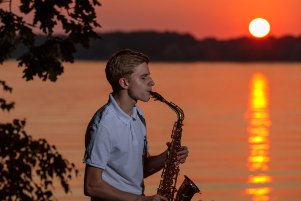 一个年轻人在傍晚日落时分吹萨克斯图片下载