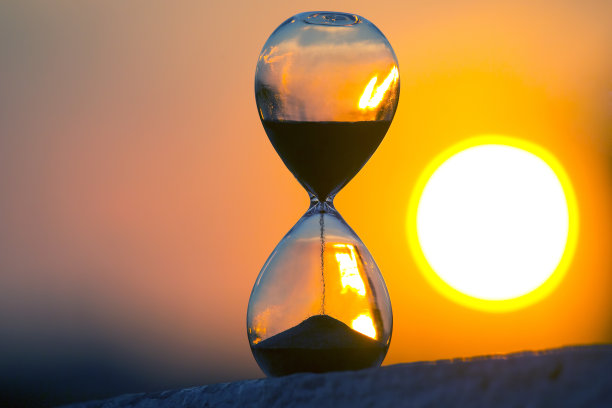 日落背景上的沙漏。生命中时间的价值。一个永恒。图片下载