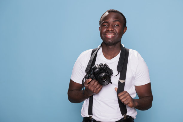 欢快的非洲民族摄影爱好者穿着时髦的t恤和背带裤图片下载