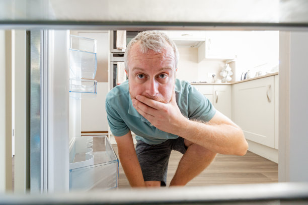 饥饿的人向空冰箱里张望图片下载