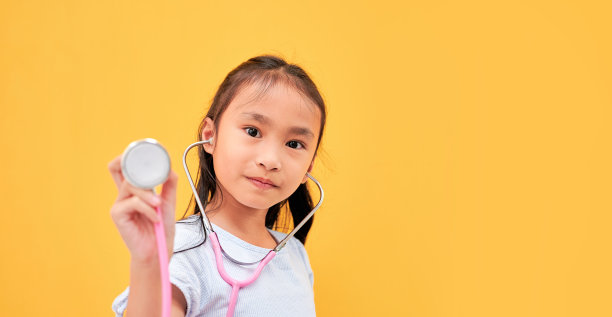 亚洲女孩戴着听诊器在黄色孤立的背景。图片下载