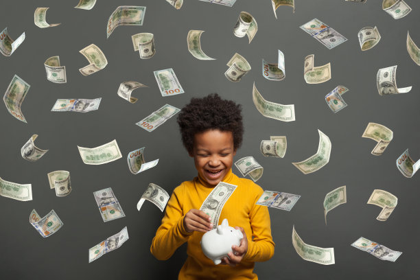 迷人的小男孩笑着落在黑色背景上的美元钱雨图片下载