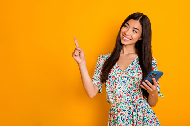 可爱女孩的照片推广推荐广告产品持有智能手机隔离在黄色的背景图片下载