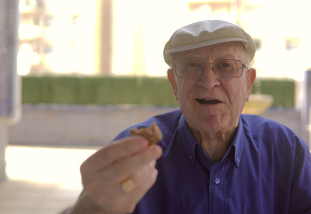 快乐的老人吃了一块饼干。有选择性的重点。图片下载