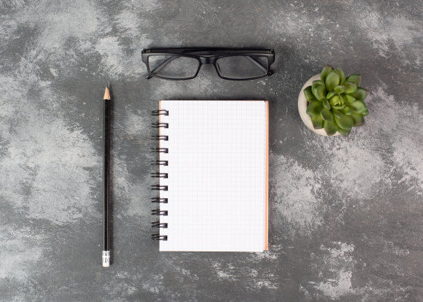 空的笔记本上有一支笔，眼镜和一个仙人掌在深灰色的背景，头脑风暴的新想法，写一个消息，休息一下，家庭办公室的桌子图片下载