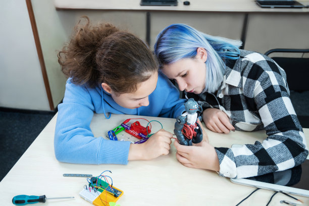 两个十几岁的女孩在机器人学校让机器人从建筑工管理，孩子们学习机器人构造。图片下载