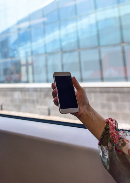 在火车上，女人手拿智能手机靠近车窗图片下载