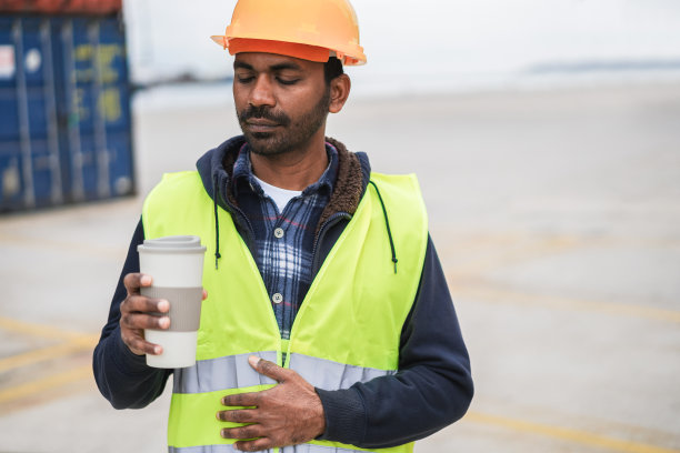在工业港口，印度工人与集装箱一起喝咖啡——关注面部图片下载