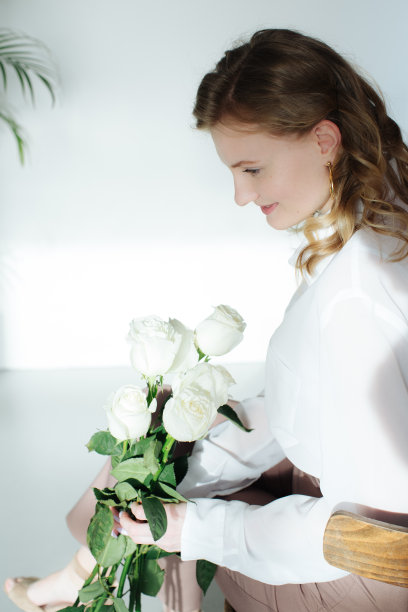 美丽快乐的女孩抱着一抱白玫瑰小心地在她的手中图片下载