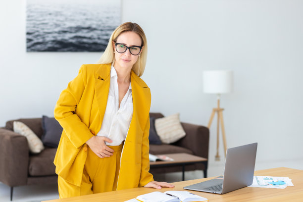 年轻女子靠在桌子上忍受着胃痛站在办公室里图片下载