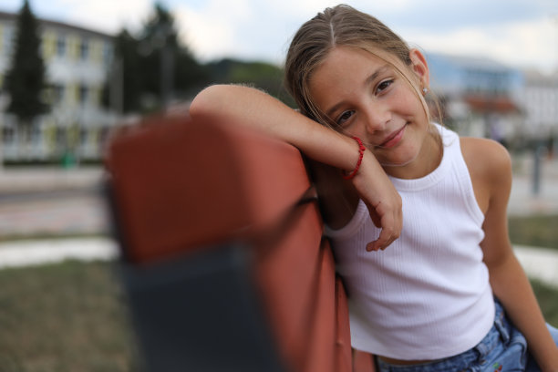 美丽的白人坐在公园长椅上。图片下载