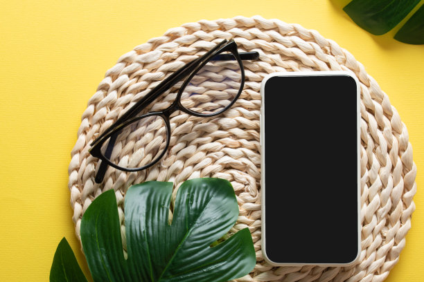 智能手机，眼镜，黄色背景的Monstera Deliciosa叶子。在工作场所写博客是一门生意。副本的空间。平铺，俯视图图片下载