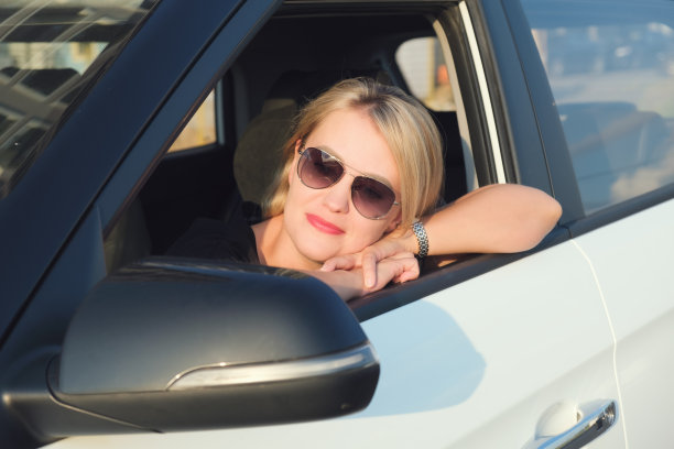 戴着墨镜的金发美女坐在她的车里图片下载