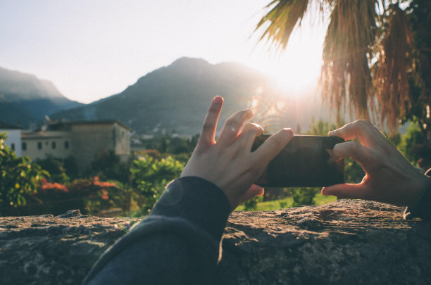 人女人在度假期间用手机智能手机拍摄美丽的日落风景图片下载