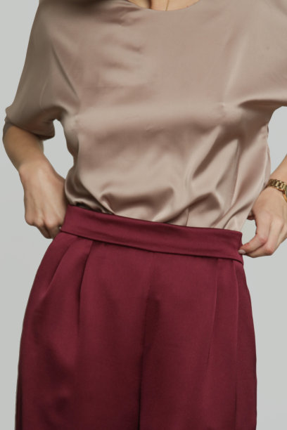 年轻女性模特穿着蝙蝠翼短袖衬衫和宽腿长裤的工作室照片系列。图片下载